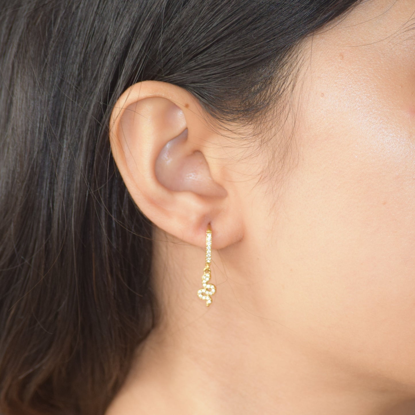Gold Serpent Huggie earring worn on ear with snake charm